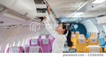 Business travel woman placing her luggage in the overhead compartment Business travel woman placing her luggage in the overhead compartment 132662698