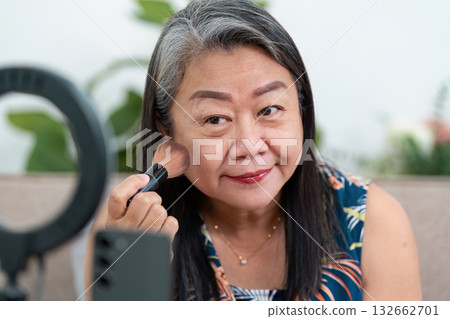 Makeup Application and Beauty Routine. A woman applying blush while preparing for her beauty session. Makeup Application and Beauty Routine. A woman applying blush while preparing for her beauty session. 132662701