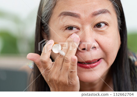Makeup Techniques and Application. A woman applying concealer under her eyes for a flawless look. 132662704