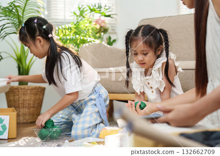Family and Sustainability. Children engaging in eco-friendly activities by creating crafts from recycled materials. 132662709