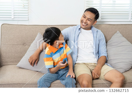 Family Connection and Relaxation. A father and son enjoying a cozy moment on the couch after gaming. 132662715