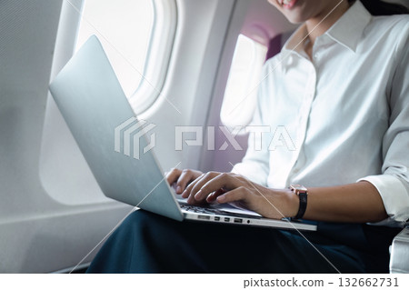 Business travel: Professional woman working on a laptop in an airplane 132662731