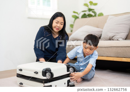 Planning and Travel. A mother and son working together to close a suitcase filled with clothes. Planning and Travel. A mother and son working together to close a suitcase filled with clothes. 132662756