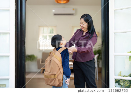 Back to School and Encouragement. A parent helps a boy with his backpack as they prepare for the school day. Back to School and Encouragement. A parent helps a boy with his backpack as they prepare for the school day. 132662763