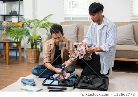 Travel Preparation and Couple Bonding. A couple packing their suitcase together, showcasing teamwork and excitement for their upcoming trip. 132662778