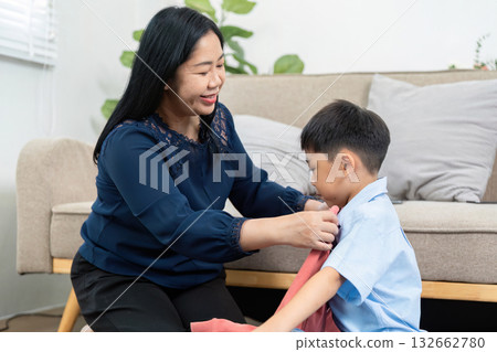 Mother and Son Preparing for Travel. A mother helps her son get dressed for an exciting journey ahead. 132662780