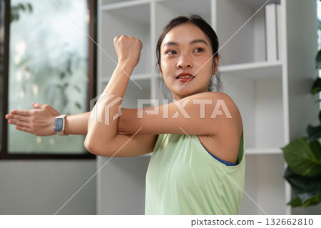 Fitness and Stretching. A woman engages in a stretching exercise at home, focusing on her arm and shoulder strength. 132662810