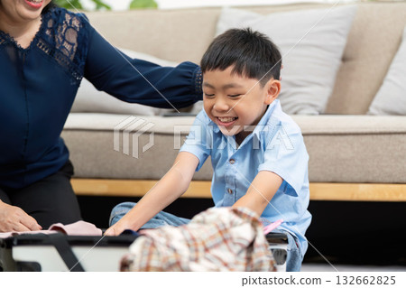 Planning and Travel. A boy enthusiastically helps his mother pack a suitcase for their trip. Planning and Travel. A boy enthusiastically helps his mother pack a suitcase for their trip. 132662825