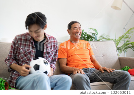 Joyful Family Moment. A father and son share a lighthearted experience while watching a soccer match at home. 132663011