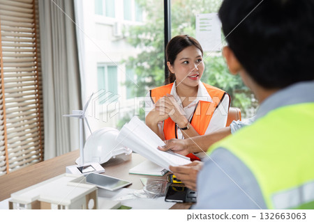 Sustainable Engineering and Project Planning. A female engineer reviewing plans with colleagues. Sustainable Engineering and Project Planning. A female engineer reviewing plans with colleagues. 132663063