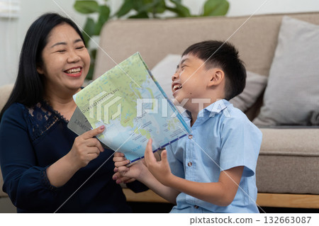 Planning and Travel. A joyful mother and son share laughter while looking at a travel map. Planning and Travel. A joyful mother and son share laughter while looking at a travel map. 132663087