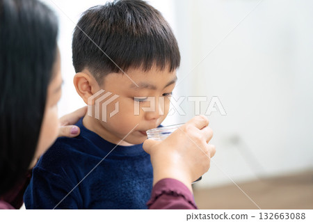 Back to School and Health. A mother helps her son drink water, promoting wellness for the new school year. 132663088