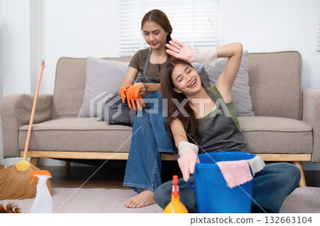 Cleaning and Joyful Moments. Friends sharing a lighthearted cleaning experience in their living room, showcasing teamwork and fun. Cleaning and Joyful Moments. Friends sharing a lighthearted cleaning experience in their living room, showcasing teamwork and fun. 132663104