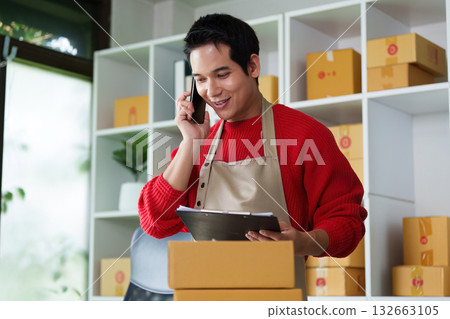 Small Business and Communication. An entrepreneur on a phone call while managing packages in his workspace. 132663105