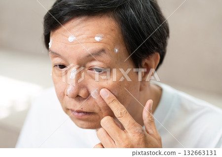 Skincare Routine and Moisturizing. A man applying targeted skincare products to specific areas of his face. 132663131