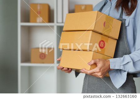 Logistics and Package Handling. A woman managing shipping packages and organizing deliveries in a commercial space. 132663160