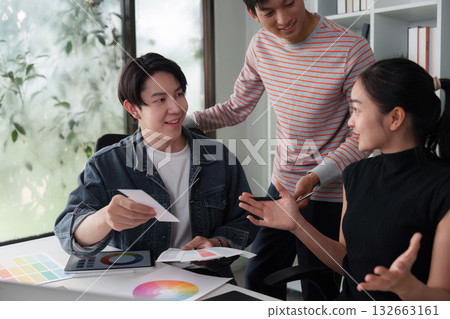 Creative Workshop and Team Dynamics. A diverse team discussing design ideas with color swatches in a modern workspace. 132663161