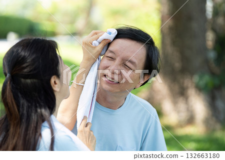 Senior Care and Wellness. A young woman helping a senior man cool down after exercise outdoors. 132663180