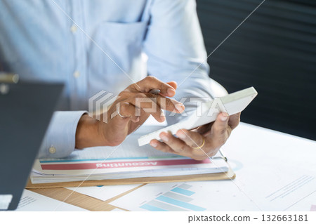 Professional Man Using Smartphone for Data Analysis. Businessman reviewing analytics on mobile device in office. 132663181