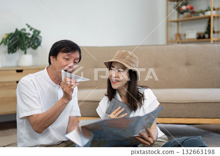 Elderly Asian couple joyfully exploring a travel map and discussing plans while holding a passport, highlighting travel excitement. Elderly Asian couple joyfully exploring a travel map and discussing plans while holding a passport, highlighting travel excitement. 132663198