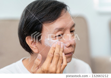 Elderly Skincare Routine. An elderly man applying moisturizer to his face, focusing on skin health. Elderly Skincare Routine. An elderly man applying moisturizer to his face, focusing on skin health. 132663212