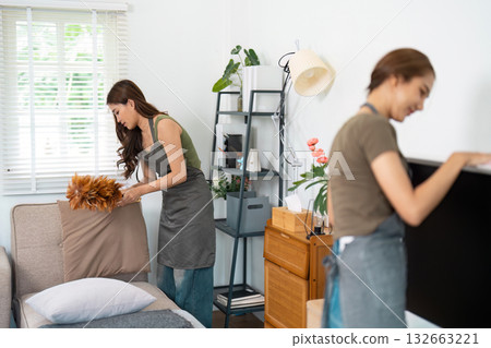 Cleaning and Home Organization. Two women tidying up their living space together, creating a fresh and inviting atmosphere. Cleaning and Home Organization. Two women tidying up their living space together, creating a fresh and inviting atmosphere. 132663221