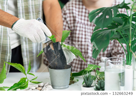 Planting and Eco-Consciousness. An adult helps a child plant in a pot, fostering a love for nature. Planting and Eco-Consciousness. An adult helps a child plant in a pot, fostering a love for nature. 132663249