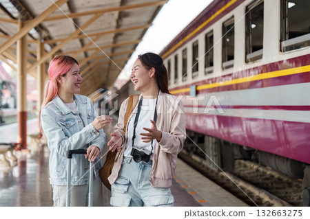 Joy and Connection. Two friends sharing a laugh and moment at the train station platform. Joy and Connection. Two friends sharing a laugh and moment at the train station platform. 132663275