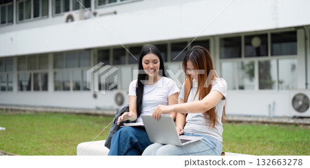 Homework and Technology. Two students efficiently working on a laptop in a university setting, focused on their studies. 132663278