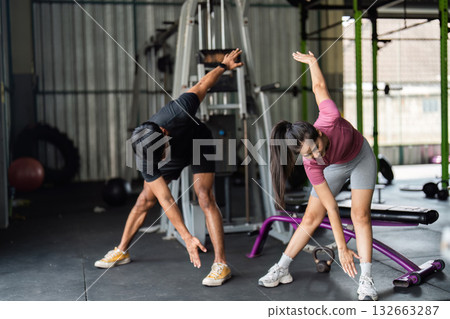 Workout and Fitness. Young couple stretching together in gym for flexibility. Workout and Fitness. Young couple stretching together in gym for flexibility. 132663287