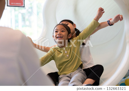 Excited Kids Sliding Down. Happy children enjoying slide at indoor playground. Excited Kids Sliding Down. Happy children enjoying slide at indoor playground. 132663321