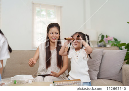 Joy and Learning. A mother and child enjoying creative play with recycled crafts. Joy and Learning. A mother and child enjoying creative play with recycled crafts. 132663340