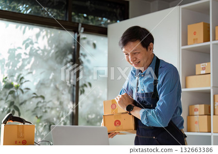 Happy small business owner carrying packages in a bright modern workspace. 132663386