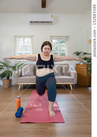 woman practicing yoga lunges on a mat at home for wellness. woman practicing yoga lunges on a mat at home for wellness. 132663389