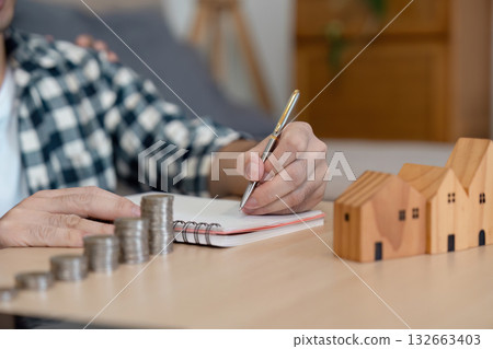LGBTQ couple planning their financial future with a notebook and coins at home LGBTQ couple planning their financial future with a notebook and coins at home 132663403