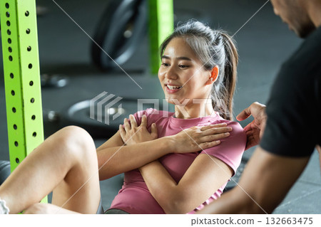 Core Workout. Smiling woman engaged in an abdominal exercise assisted by a partner. Core Workout. Smiling woman engaged in an abdominal exercise assisted by a partner. 132663475