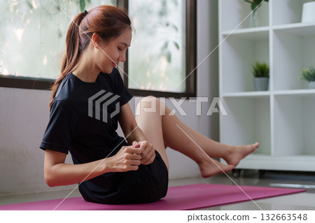 Wellness and Fitness Routine. A young woman practicing yoga on a mat, focusing on her posture and balance. 132663548