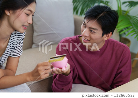 Savings and Spending. A couple learning about savings techniques while having fun with their pink piggy bank. Savings and Spending. A couple learning about savings techniques while having fun with their pink piggy bank. 132663552