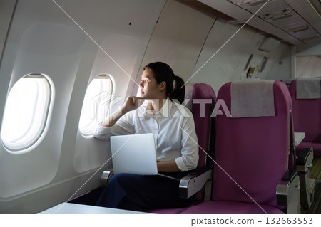 Business Travel. Thoughtful woman reflecting while gazing out the airplane window. Business Travel. Thoughtful woman reflecting while gazing out the airplane window. 132663553