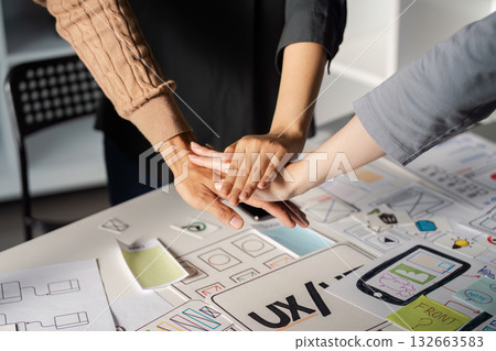 Team joining hands in solidarity during UX UI design collaboration. 132663583