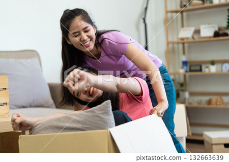Playful fun A lesbian couple enjoying a moving box adventure Playful fun A lesbian couple enjoying a moving box adventure 132663639