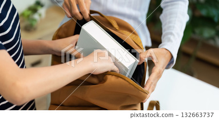 Back to School and Organizing Supplies. Two hands placing books into a backpack for school. Back to School and Organizing Supplies. Two hands placing books into a backpack for school. 132663737