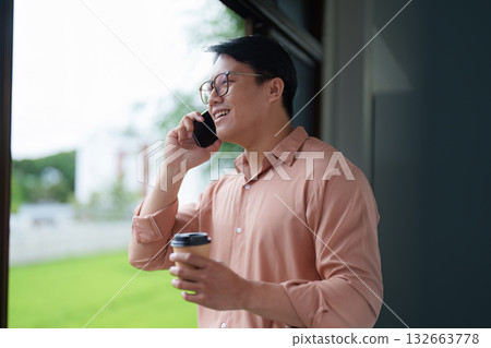 Young Professional on Phone Call in Bright Workspace Young Professional on Phone Call in Bright Workspace 132663778