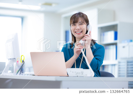 Business woman talking on the phone while looking at a computer Business woman talking on the phone while looking at a computer 132664765