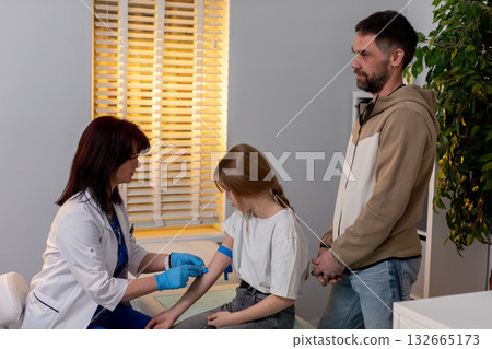 A medical professional gives a vaccination to a young patient in a clinic appointment 132665173