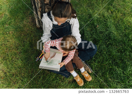 Mother and Toddler Drawing Together in a Summer Park. Parenting and Childhood Development Concept Mother and Toddler Drawing Together in a Summer Park. Parenting and Childhood Development Concept 132665763