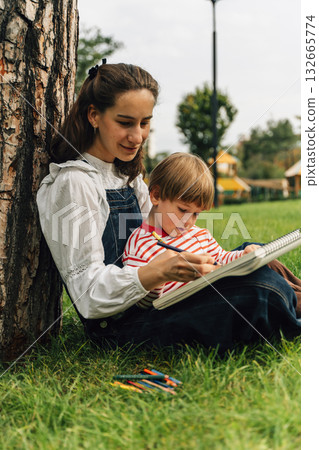 Mother and Toddler Drawing Together in a Summer Park. Parenting and Childhood Development Concept Mother and Toddler Drawing Together in a Summer Park. Parenting and Childhood Development Concept 132665774