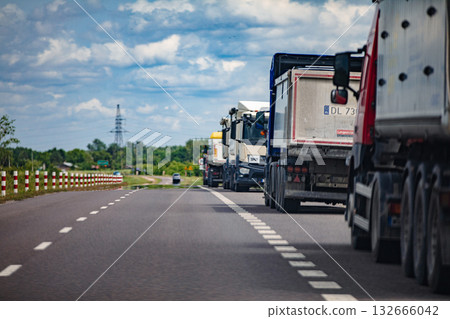 Large Heavy Trucks Drive Along a Beautiful Scenic Highway Beneath Clear Blue Skies 132666042