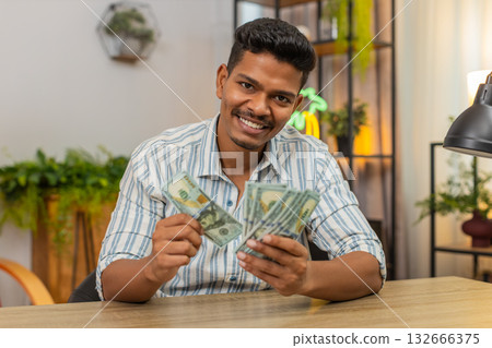Indian man counts dollar cash salary bonus plans invest smiles feels proud profit wealth success joy 132666375