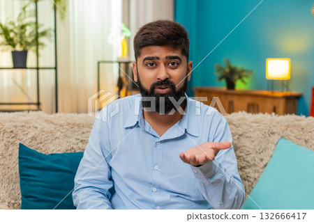 Indian man rolls eyes ironic reaction shows disbelief sarcasm during smartphone conversation indoors Indian man rolls eyes ironic reaction shows disbelief sarcasm during smartphone conversation indoors 132666417